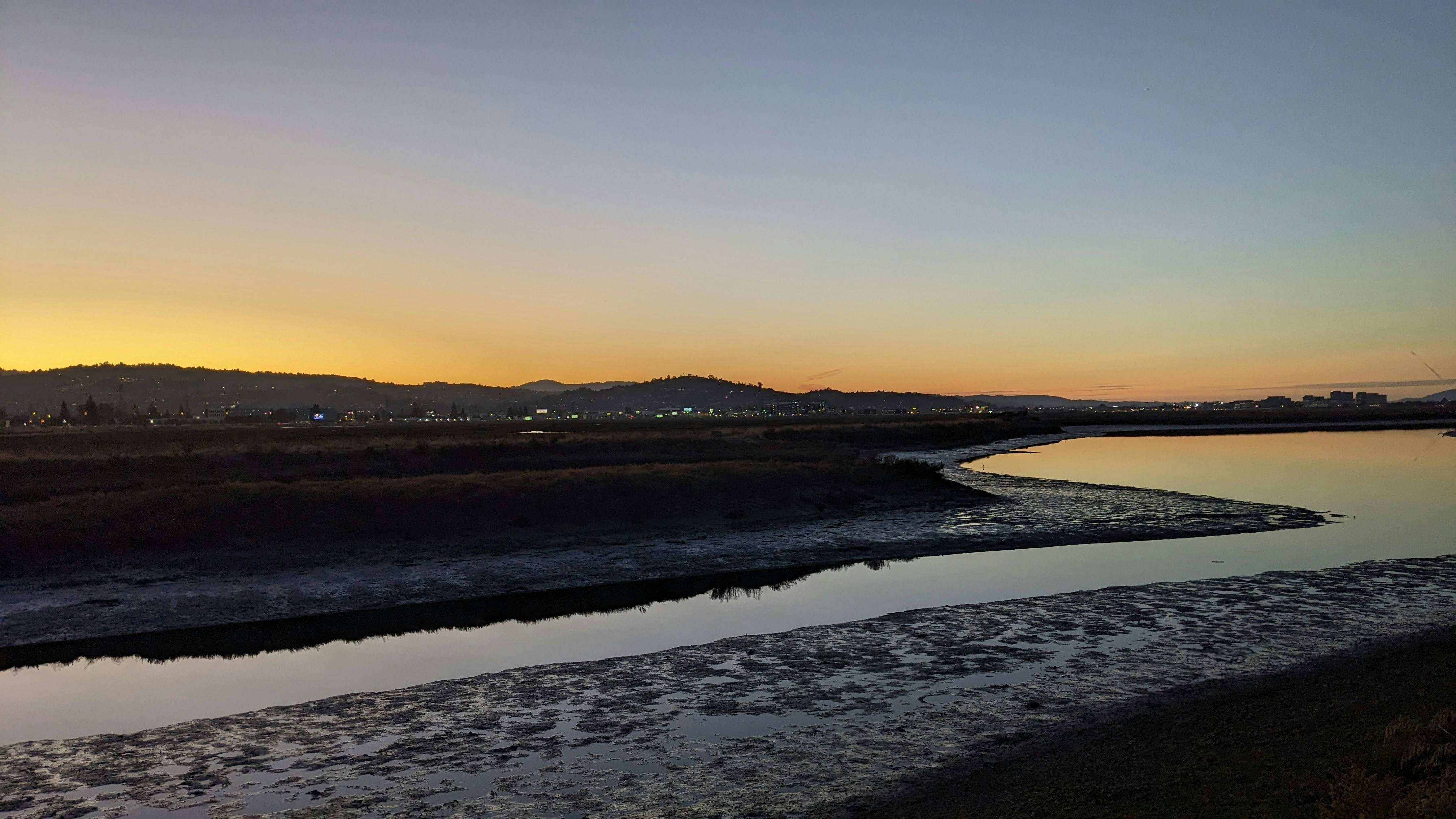 a body of water with a hill in the background, 