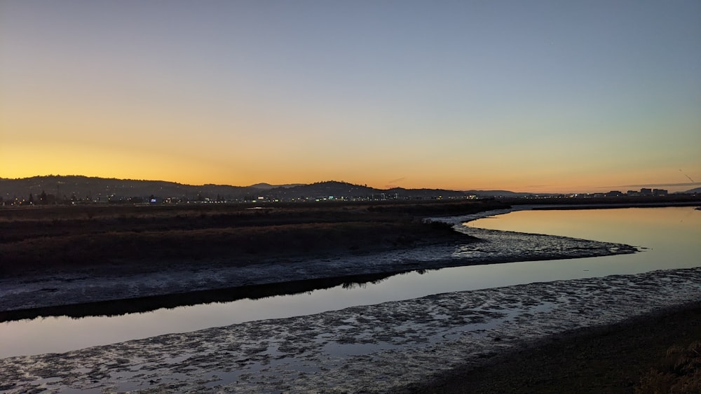 a body of water with a hill in the background