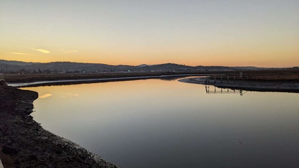 a body of water with a hill in the background