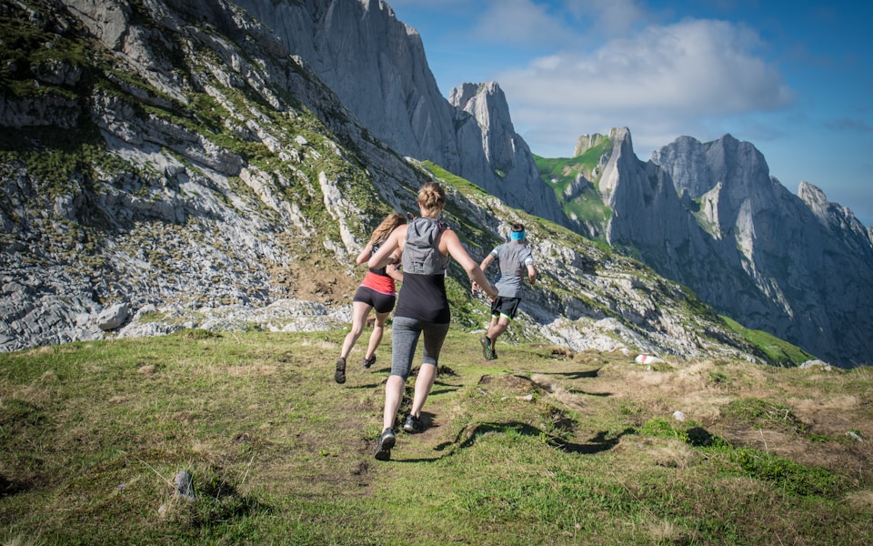 Three friends running on a mountain trail, symbolizing the endurance and vitality needed to combat fatigue