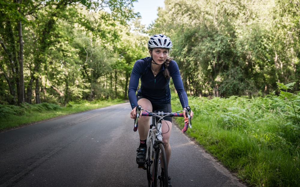 a woman riding a bike down a country road