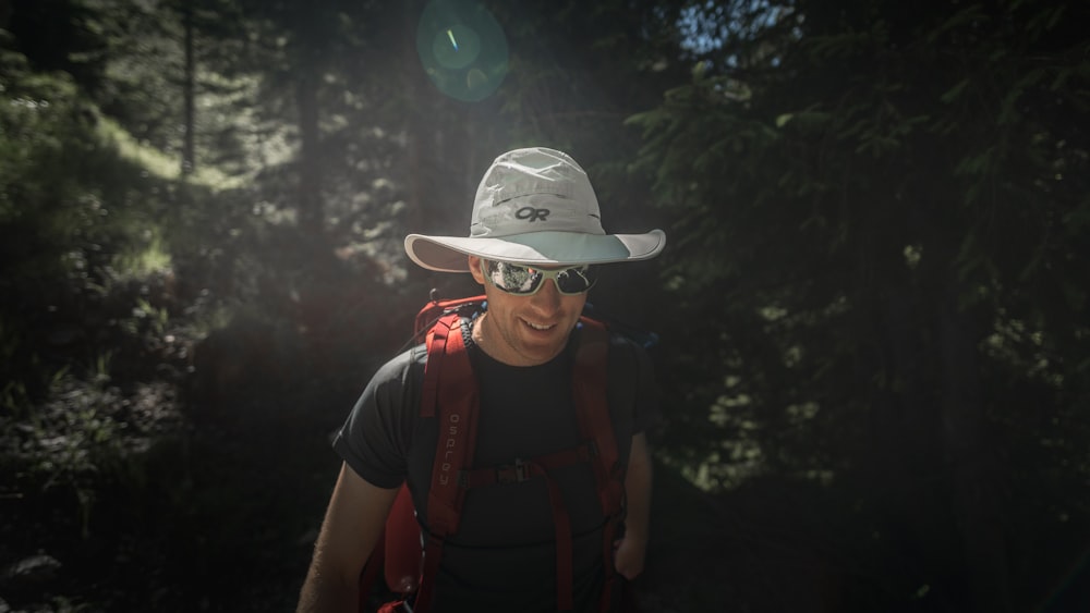 a man wearing a hat and sunglasses in the woods