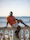a man sitting on a railing next to the ocean