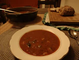 A cozy lunch setup featuring a hearty vegetable soup in a ceramic bowl with crusty bread on the side.