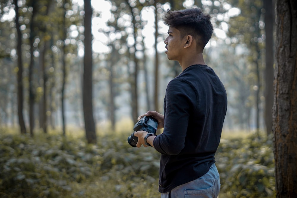 a man standing in a forest holding a camera