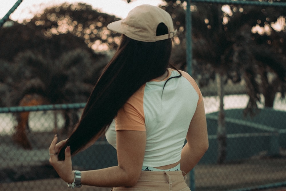 a woman with long hair standing in front of a fence