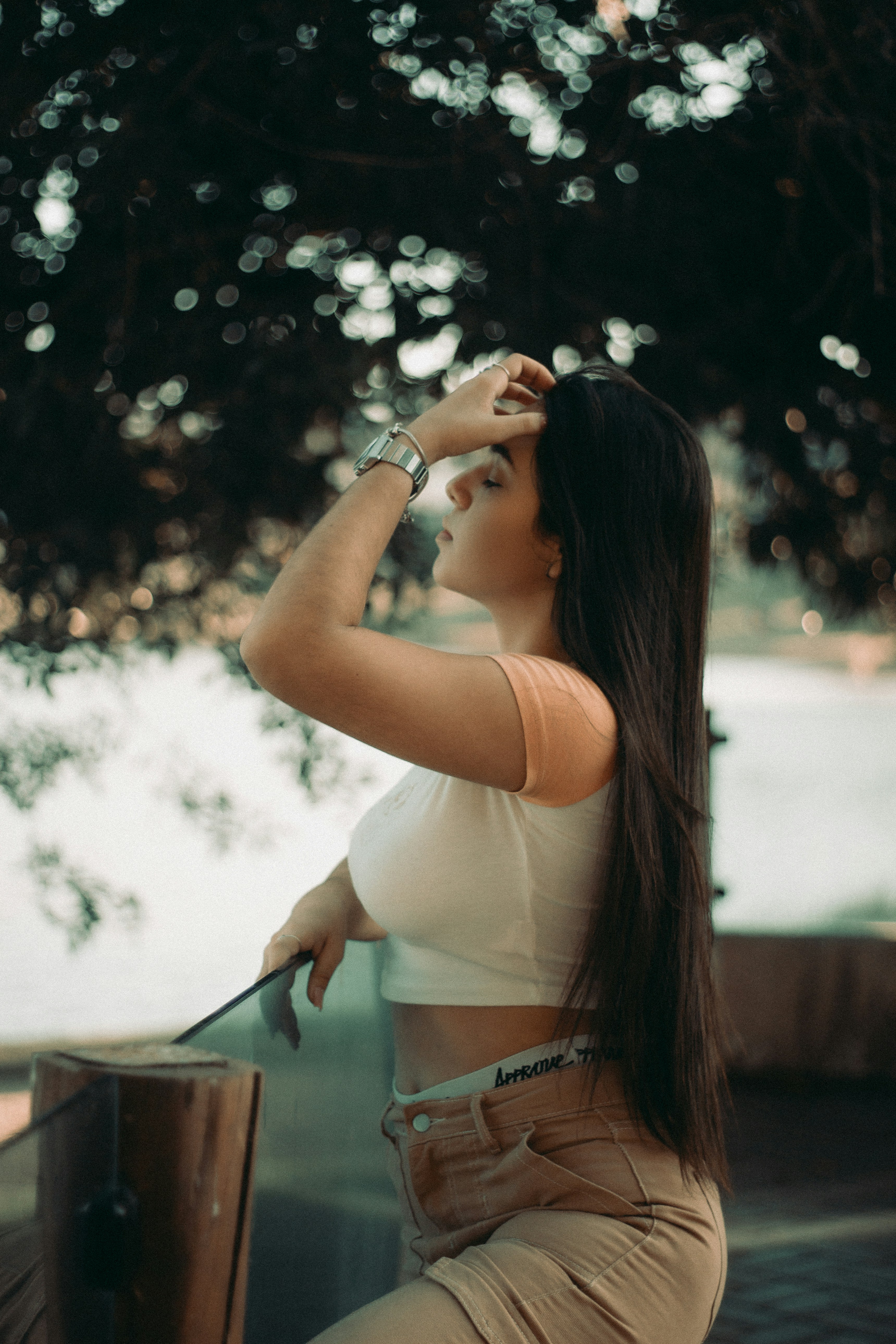 a woman sitting on a ledge next to a tree