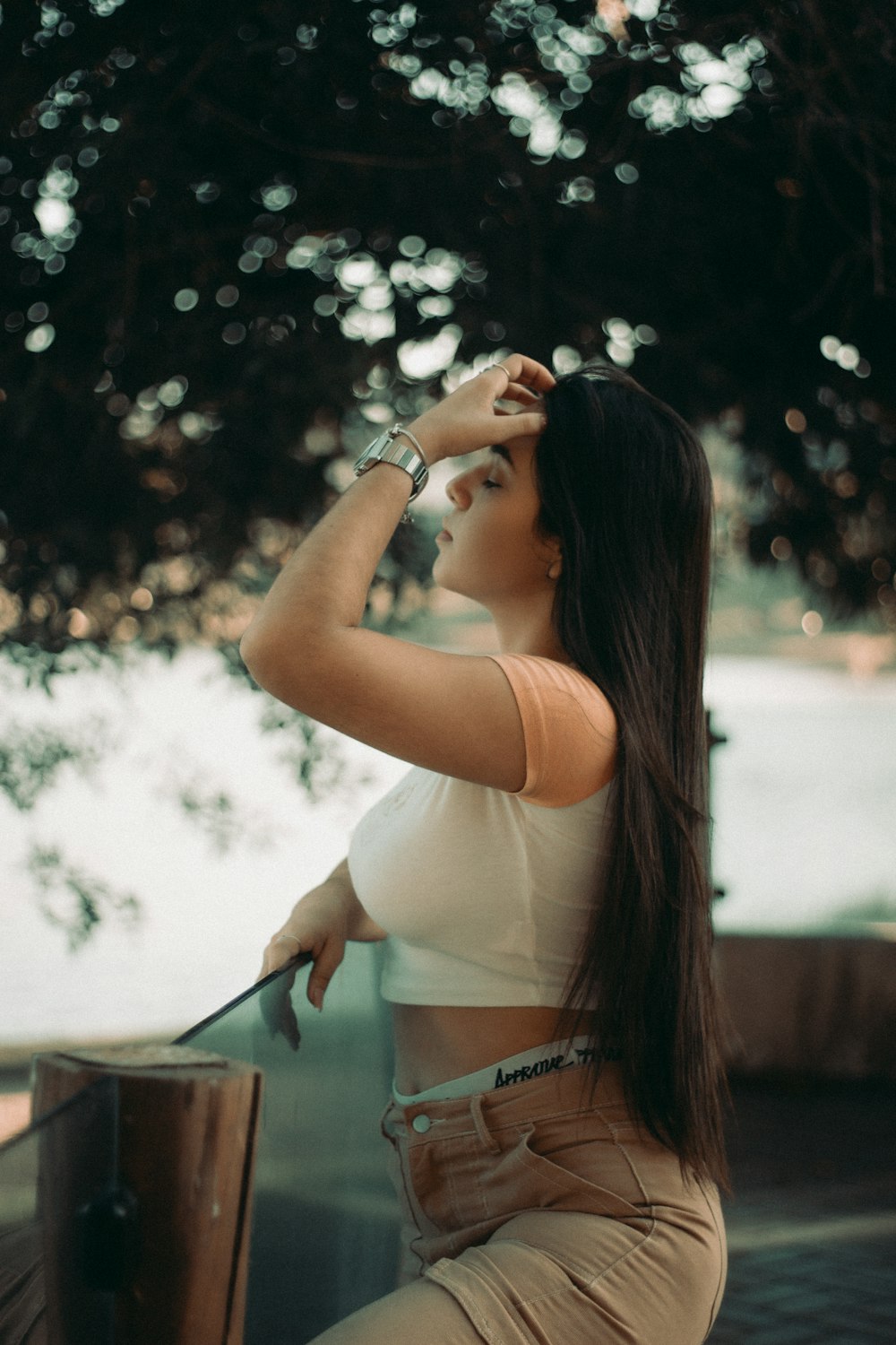 a woman sitting on a ledge next to a tree