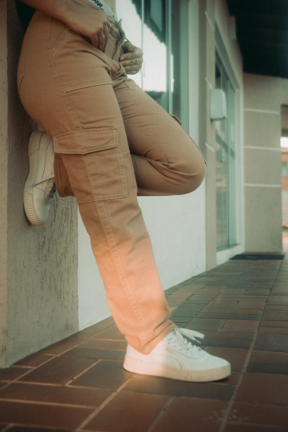 a person leaning against a wall with their legs crossed