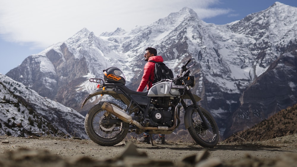Ein Mann steht neben einem Motorrad auf dem Gipfel eines Berges