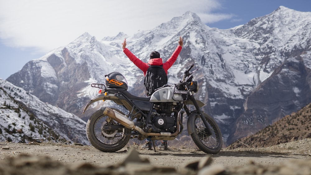 a person standing next to a motorcycle on a dirt road