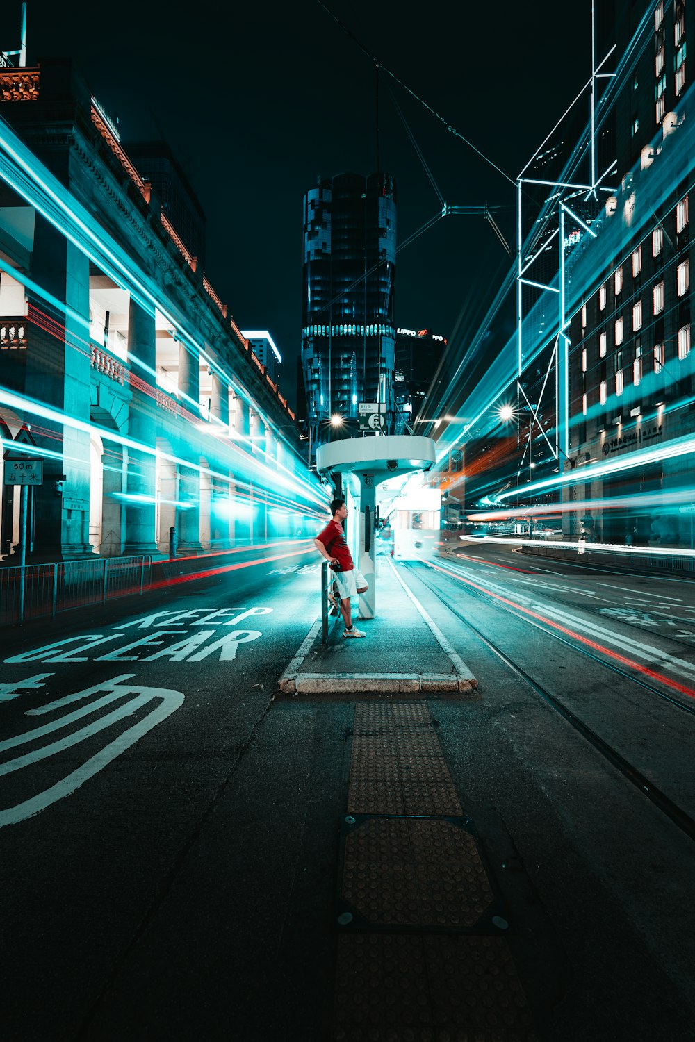 a person standing on a sidewalk in a city at night