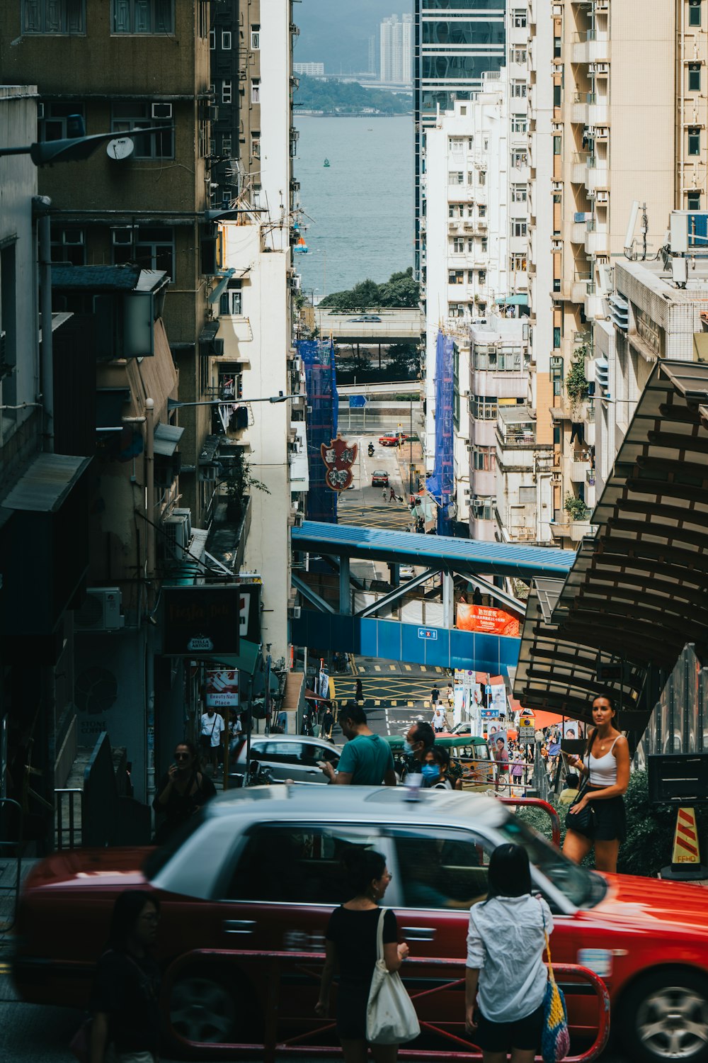 a red car driving down a street next to tall buildings