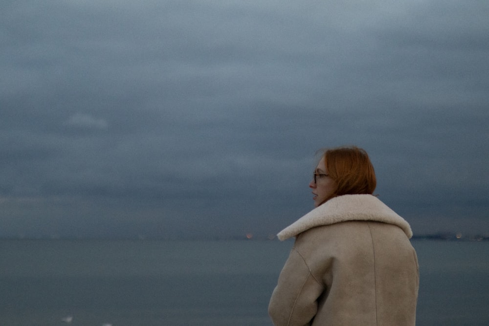 a woman standing on a beach looking out at the ocean