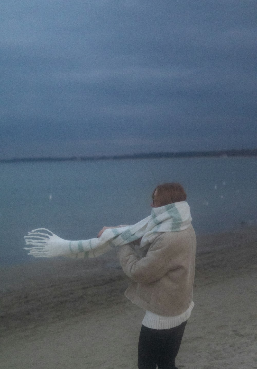 a person standing on a beach with a scarf around their neck