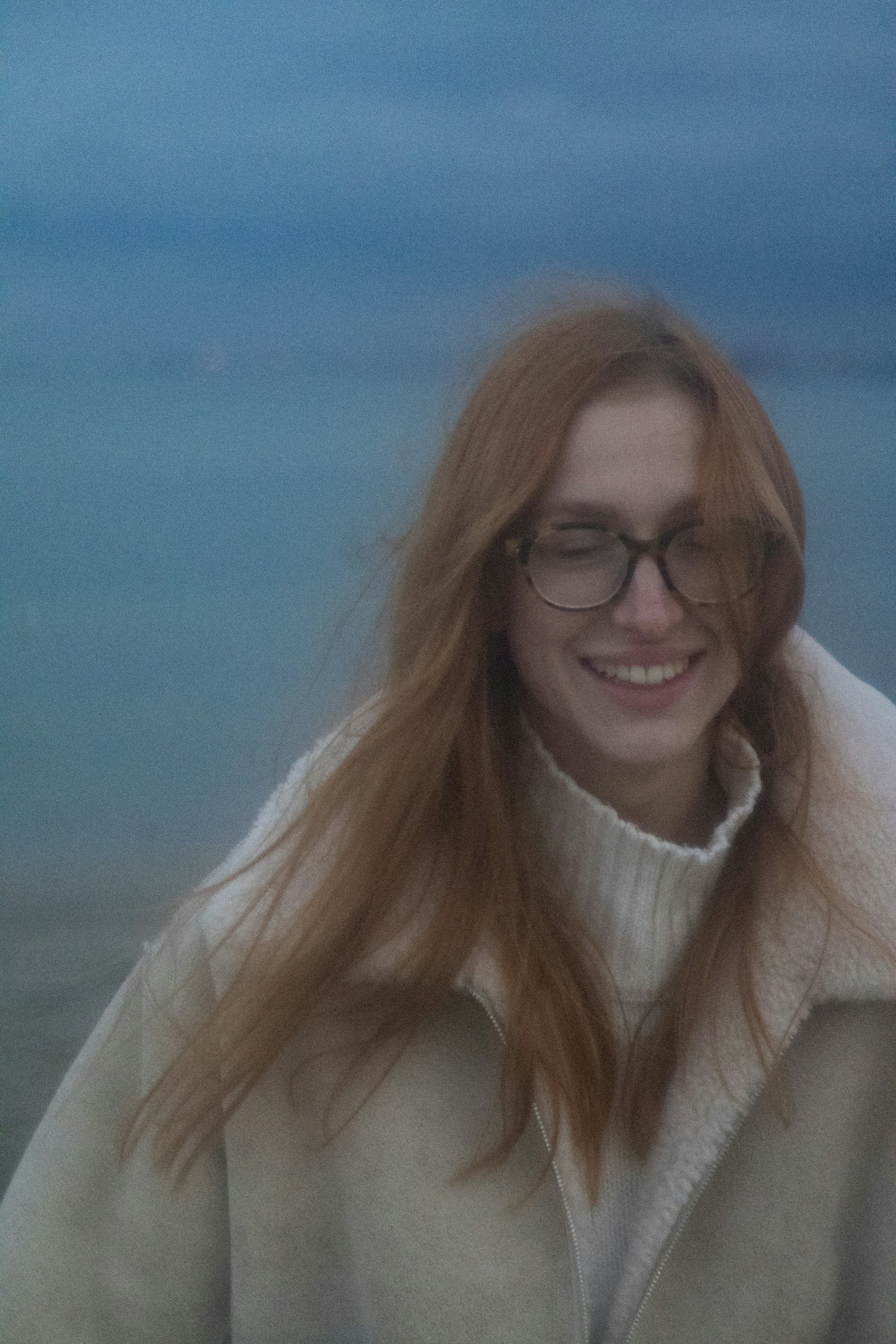 a woman with long red hair and glasses smiling