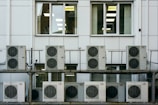 Photo of a technician from ψυκτικός λάρισα installing an air conditioning unit in a hotel room.