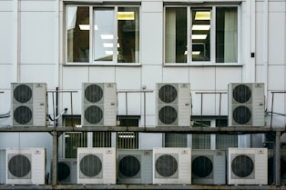 Close-up of a professional repairing an office air conditioning unit with tools.