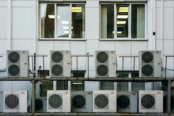 Close-up of a professional repairing an office air conditioning unit with tools.