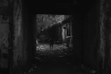 A grainy, found-footage style frame showing a lone figure walking through a dimly lit urban alley.