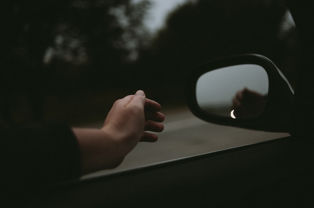 a person holding their hand out of a car window
