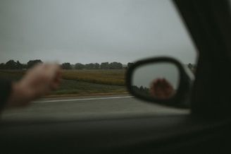 a person's reflection in the side view mirror of a car