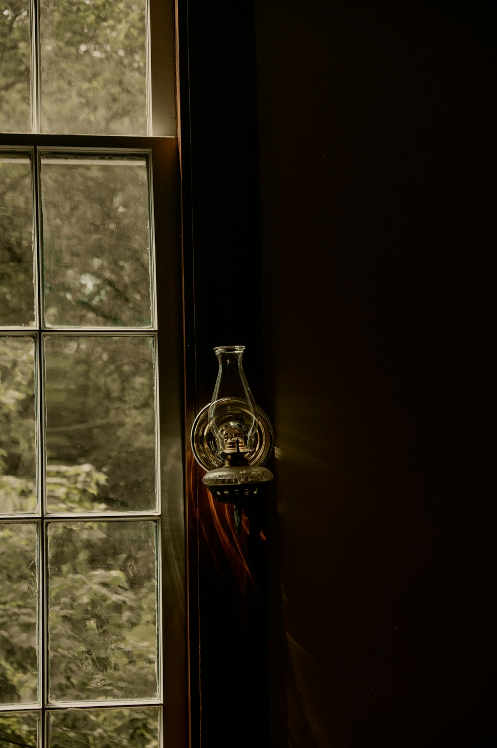 un jarrón de vidrio sentado en el alféizar de una ventana junto a una ventana