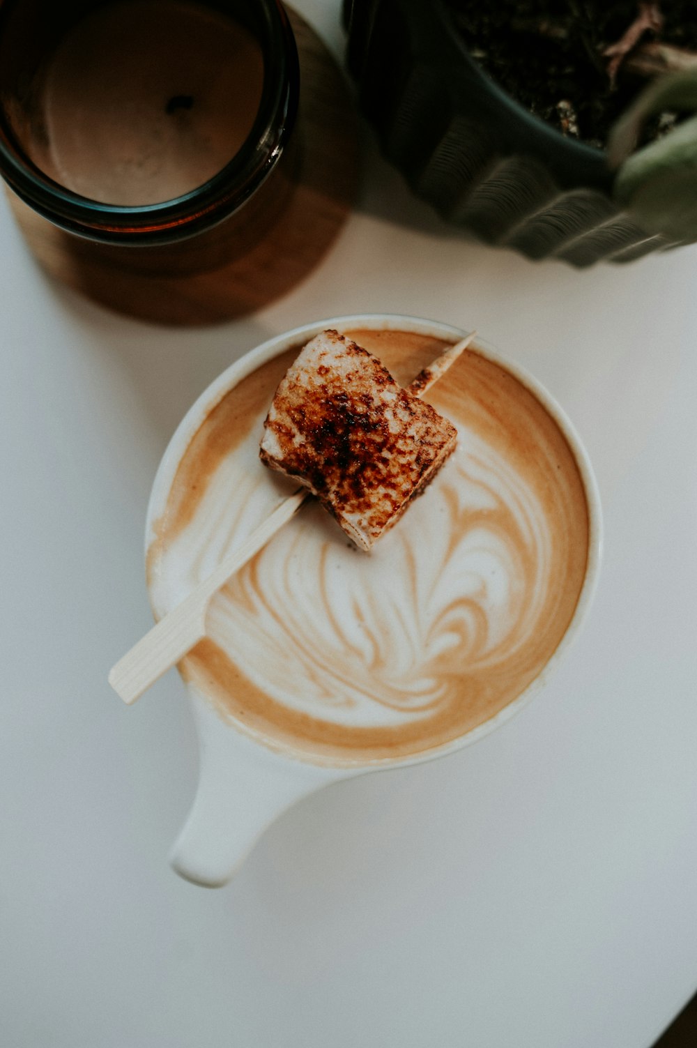 a cup of coffee with a piece of cake on top of it