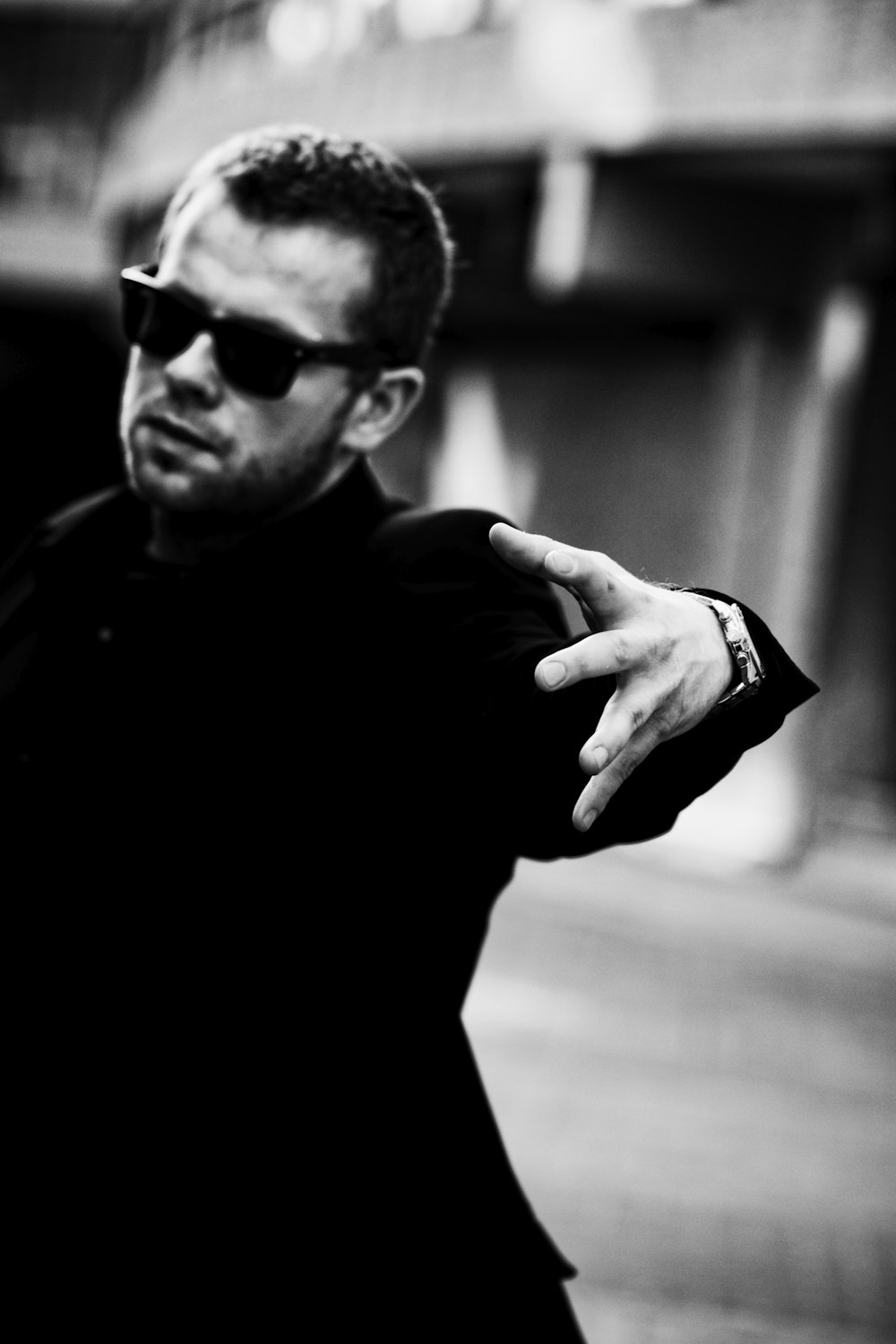 a man in a black shirt and sunglasses pointing at something