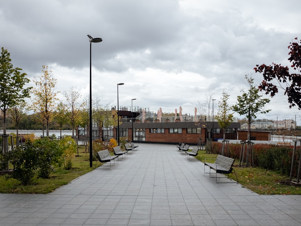 a walkway lined with benches next to a park