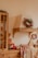 A cozy kitchen setting featuring a wooden cabinet and countertop. Decorative wreaths with red berries and green foliage adorn the walls. There is a collection of wooden cutting boards and kitchen utensils, with red mugs and a fresh loaf of bread placed on a patterned cloth. A warm, inviting ambiance is emphasized by rustic elements and natural materials.