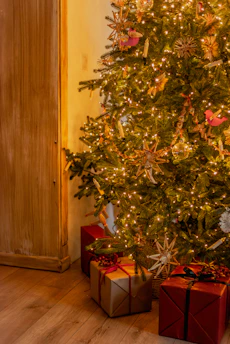A cozy family gathered around a decorated Christmas tree exchanging wrapped gifts.