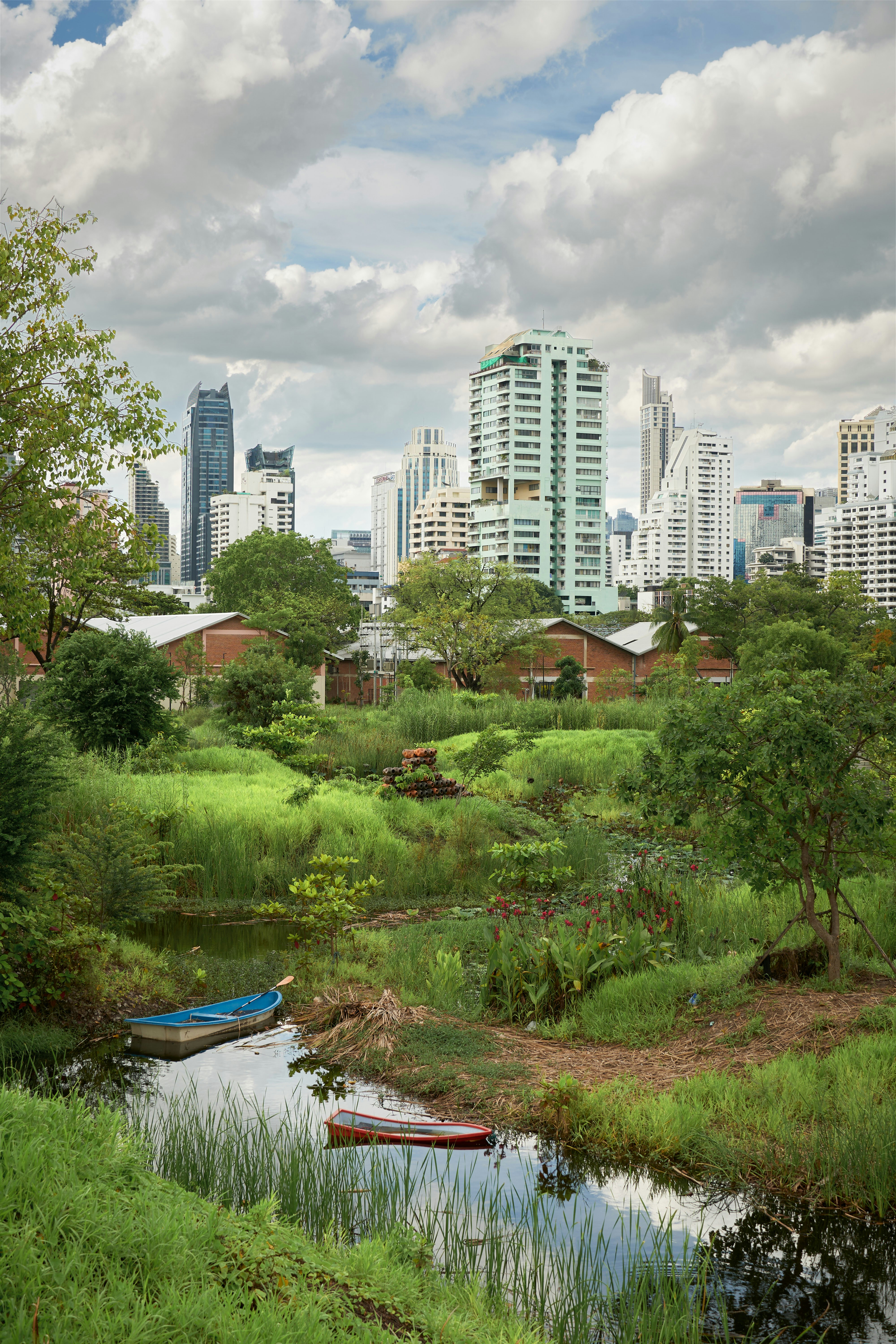 a river running through a lush green field next to tall buildings