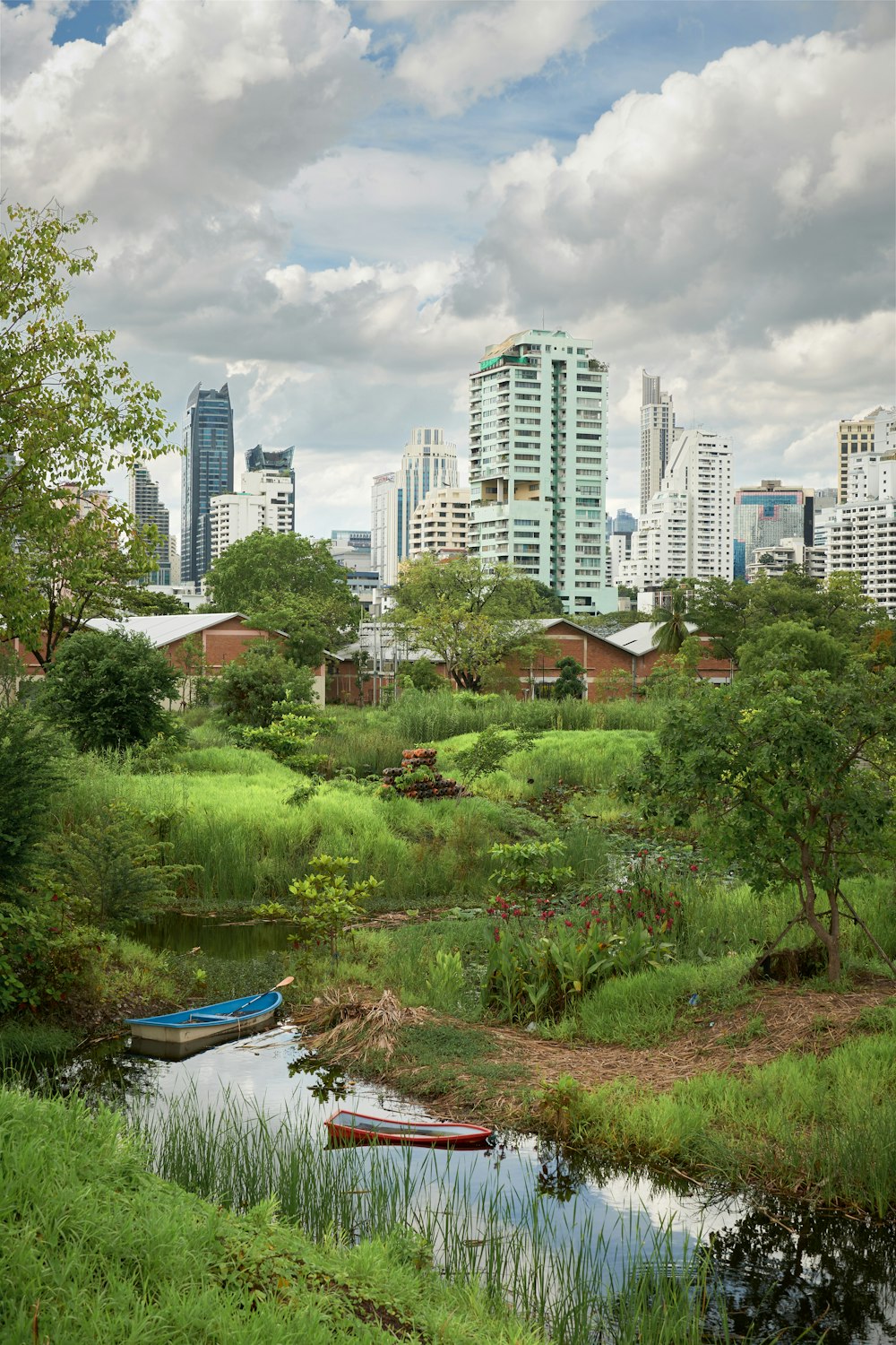 a river running through a lush green field next to tall buildings