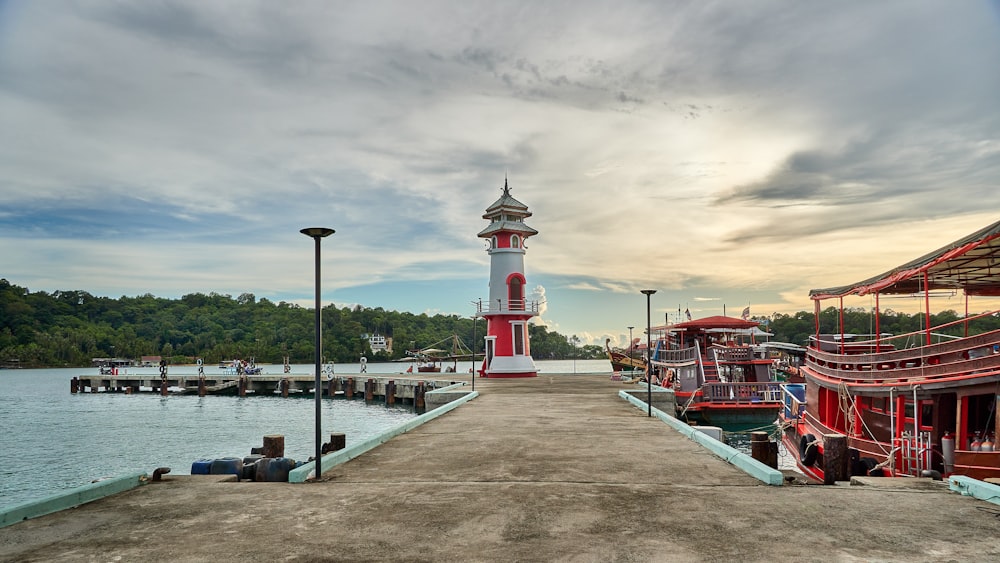 a red and white lighthouse sitting on top of a pier