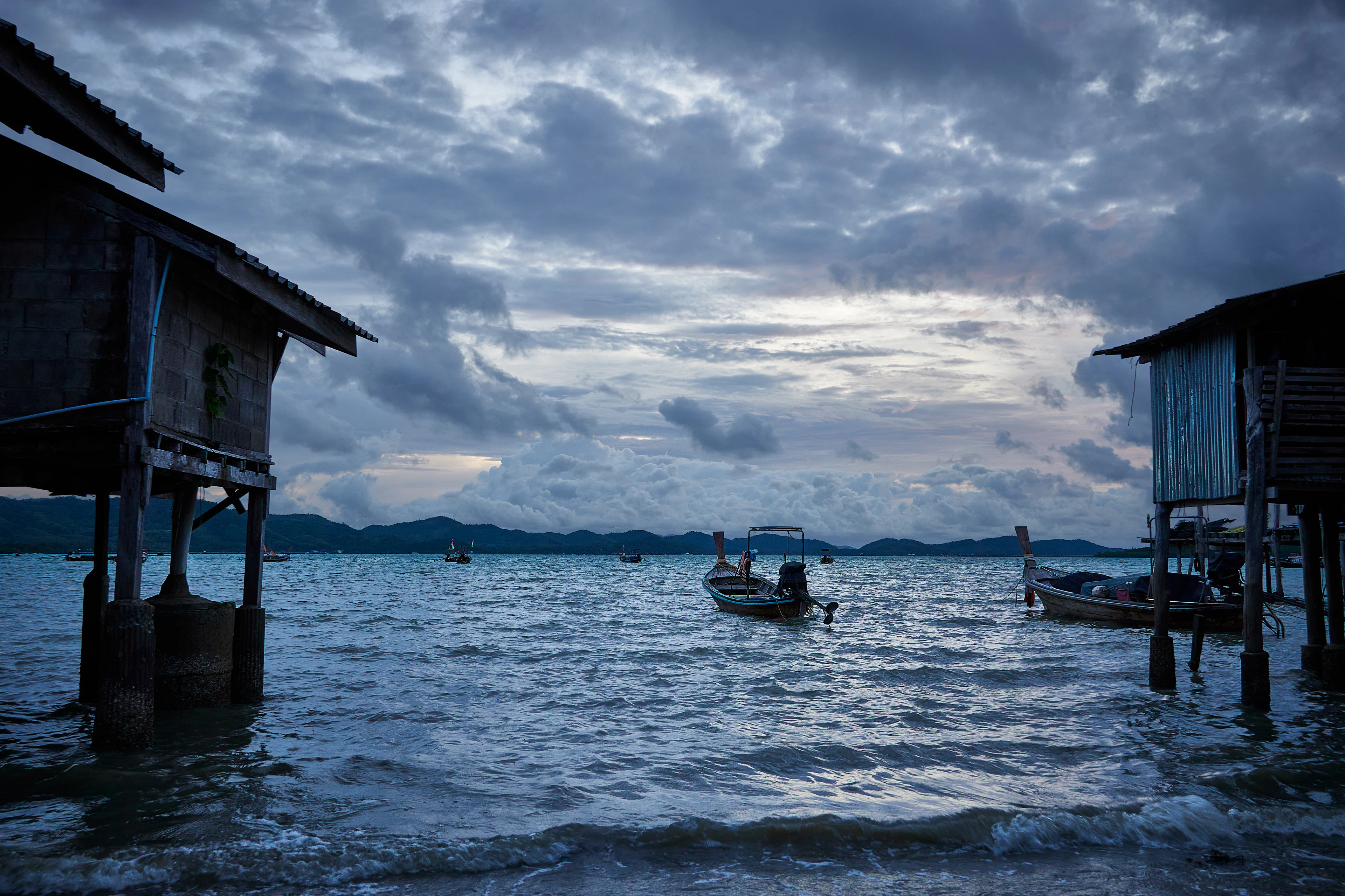 Stilt houses and fishing boats off the shore of Koh Yao Noi on an overcast evening