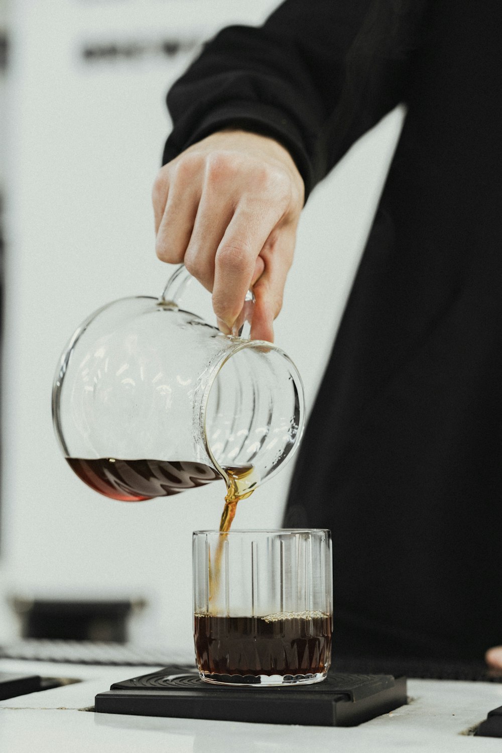 a person pouring coffee into a glass mug