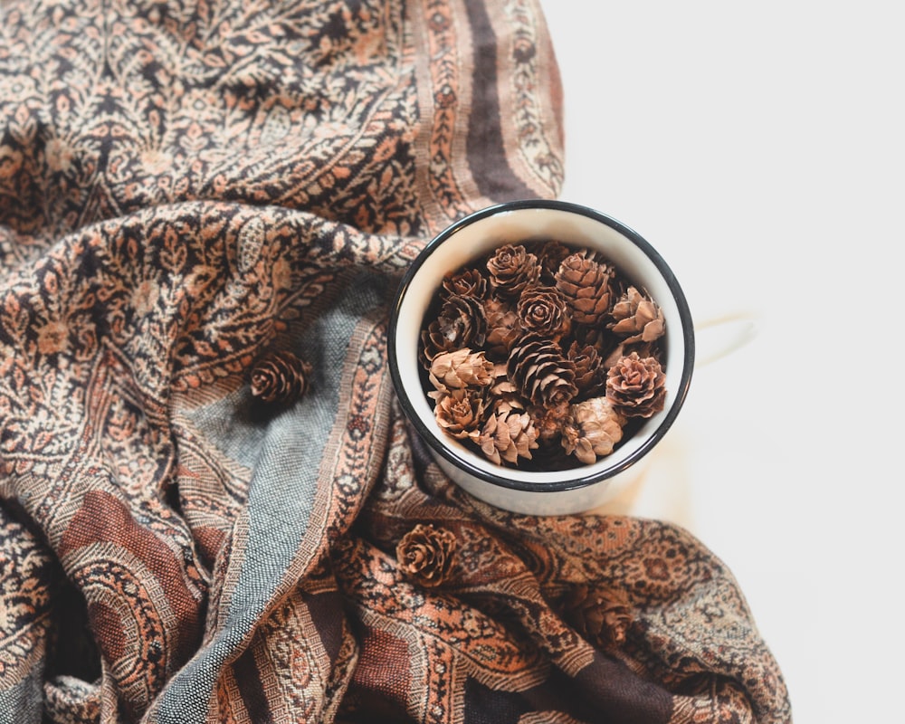 a bowl filled with pine cones on top of a blanket