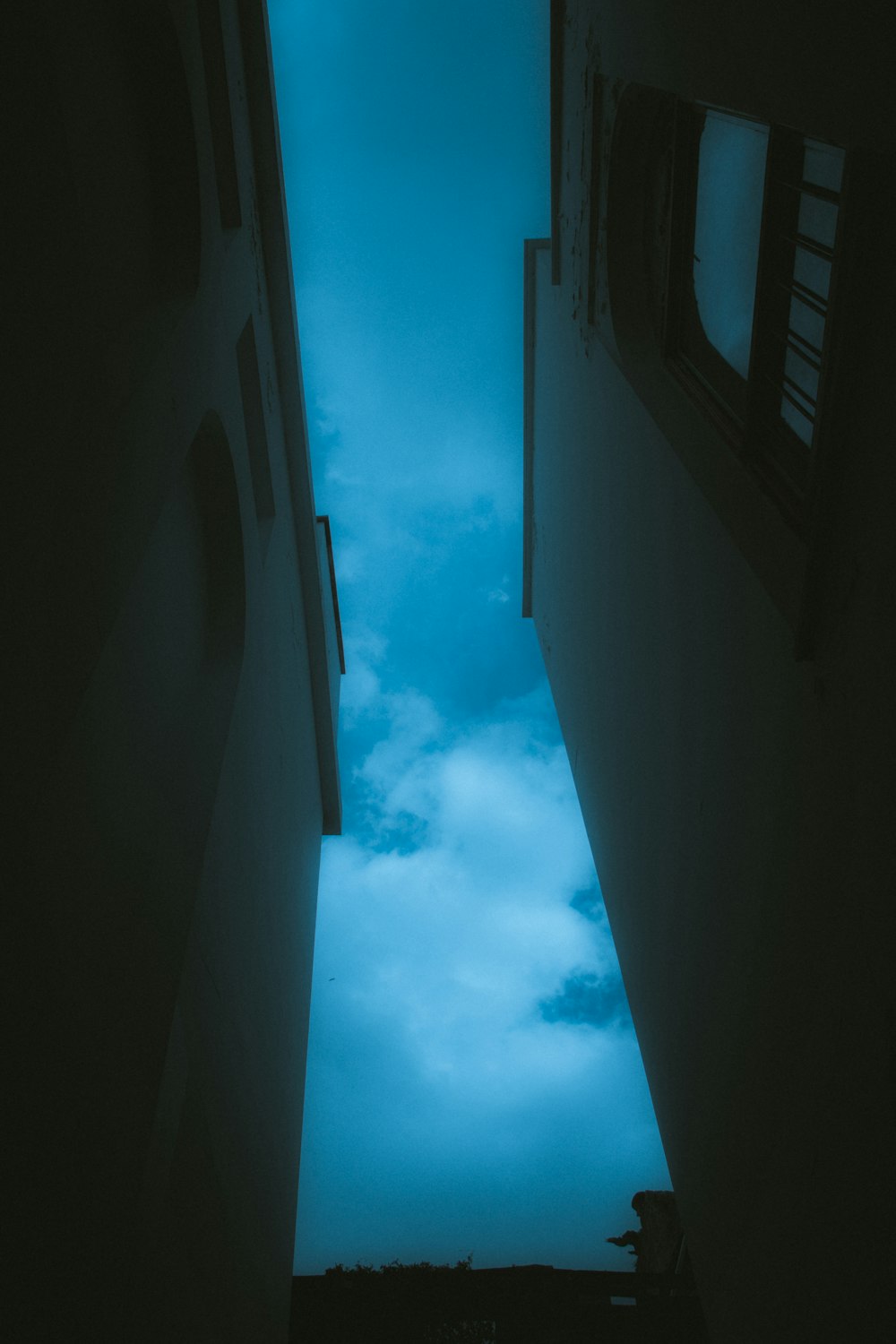 a narrow hallway leading to a sky filled with clouds