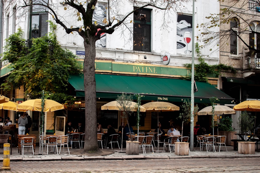 a group of people sitting at tables under umbrellas