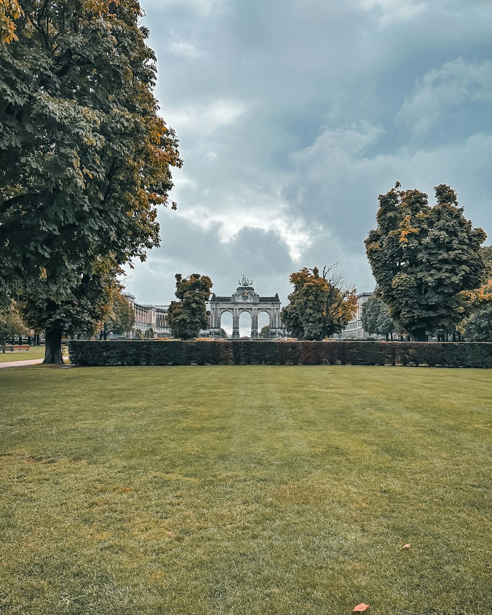 a large grassy field with trees and a building in the background