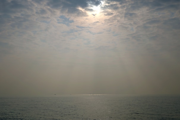 Sunlight filtering through soft clouds over a tranquil sea, evoking calm and clarity.