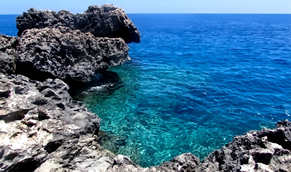 a body of water surrounded by rocks and blue water