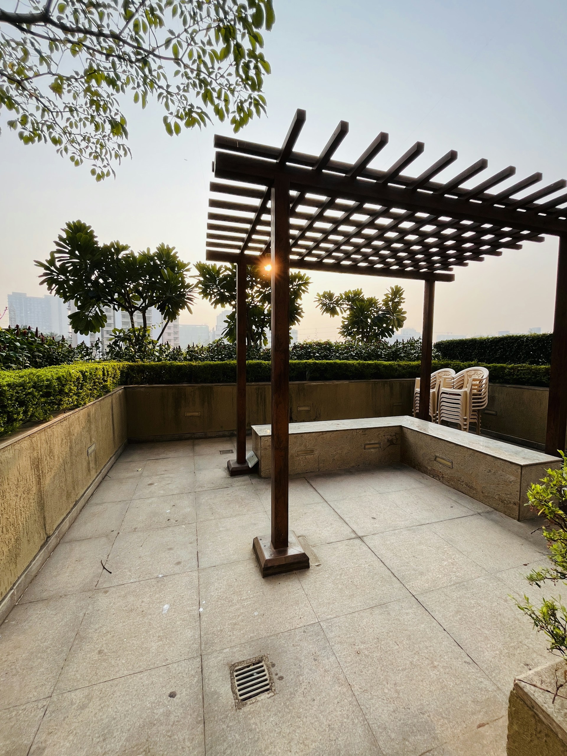 a patio with a pergolated roof and a bench