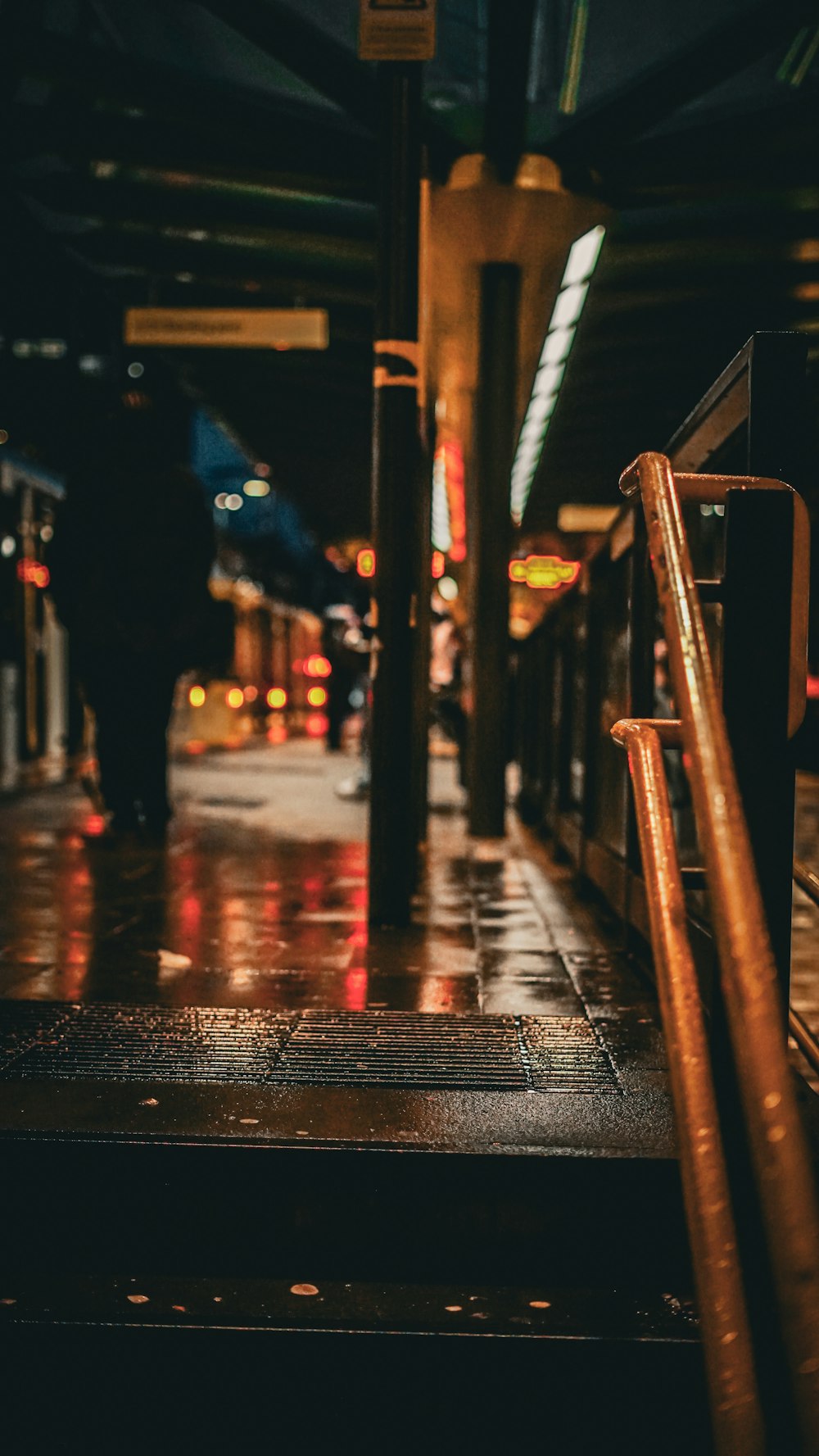 a person walking down a wet sidewalk next to a train station