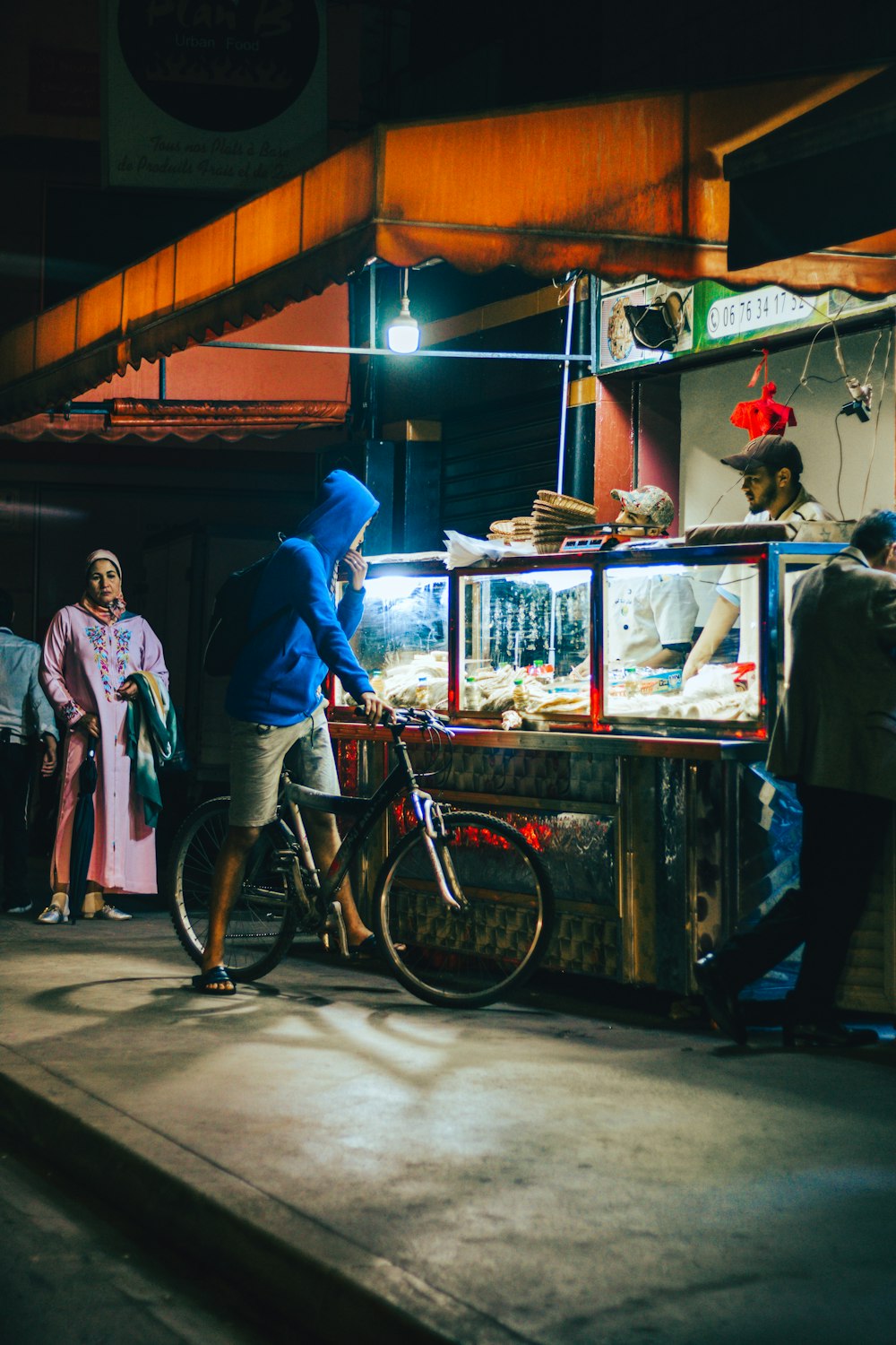 a man standing next to a bike in front of a food stand