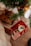 A cozy holiday scene featuring neatly wrapped gifts under a Christmas tree. One gift is wrapped in festive paper with a red ribbon, displaying a candle decorated with holly. The other gift is wrapped in brown paper with a dark brown ribbon, creating a warm and inviting atmosphere.