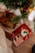 A cozy holiday scene featuring neatly wrapped gifts under a Christmas tree. One gift is wrapped in festive paper with a red ribbon, displaying a candle decorated with holly. The other gift is wrapped in brown paper with a dark brown ribbon, creating a warm and inviting atmosphere.