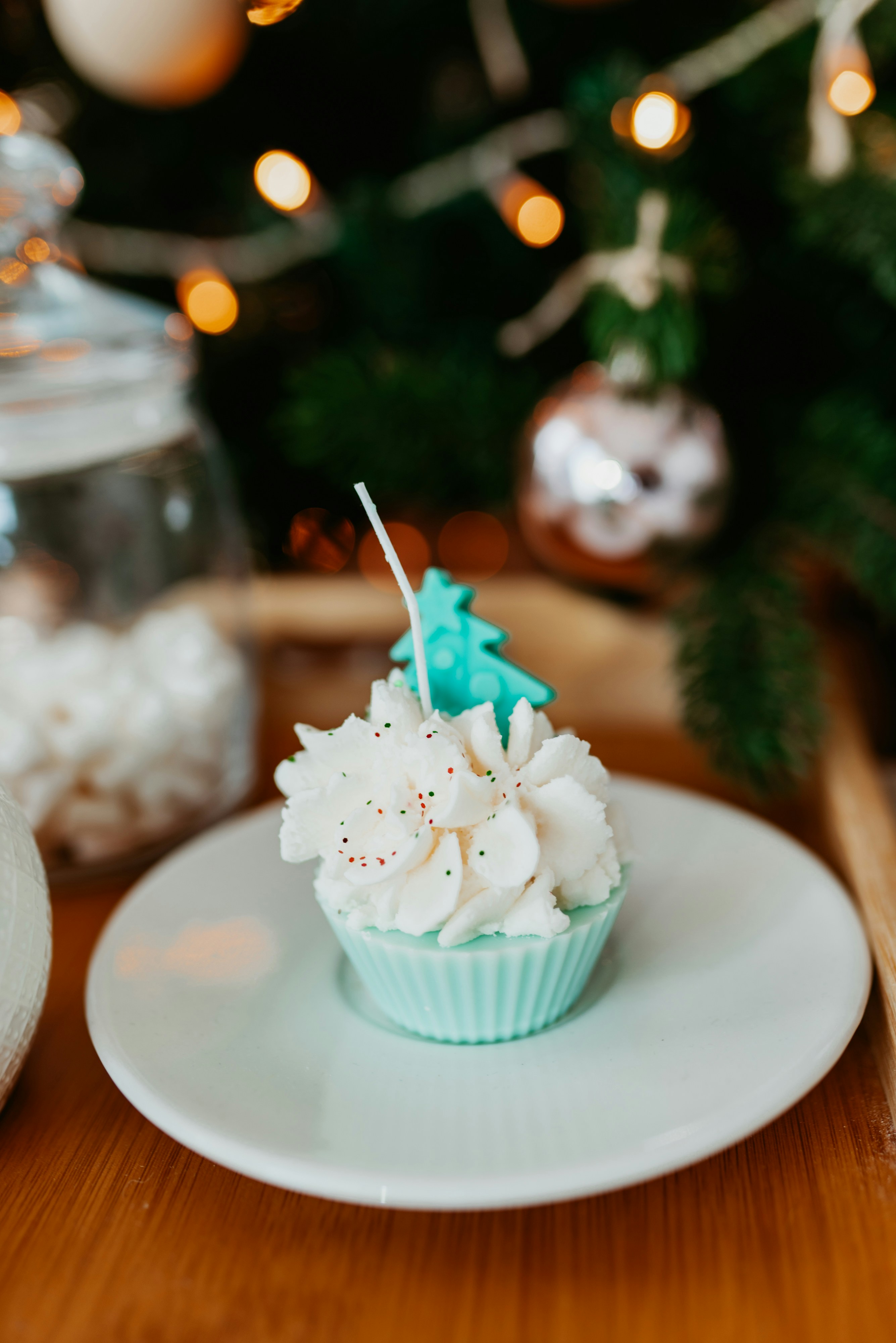a cupcake sitting on a plate next to a christmas tree