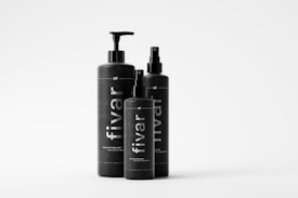Three black bottles of varying sizes with minimalist design are arranged together. Each bottle features the brand name 'fivar' vertically printed in white. The bottles have different types of dispensers, indicating they may be for different types of products.